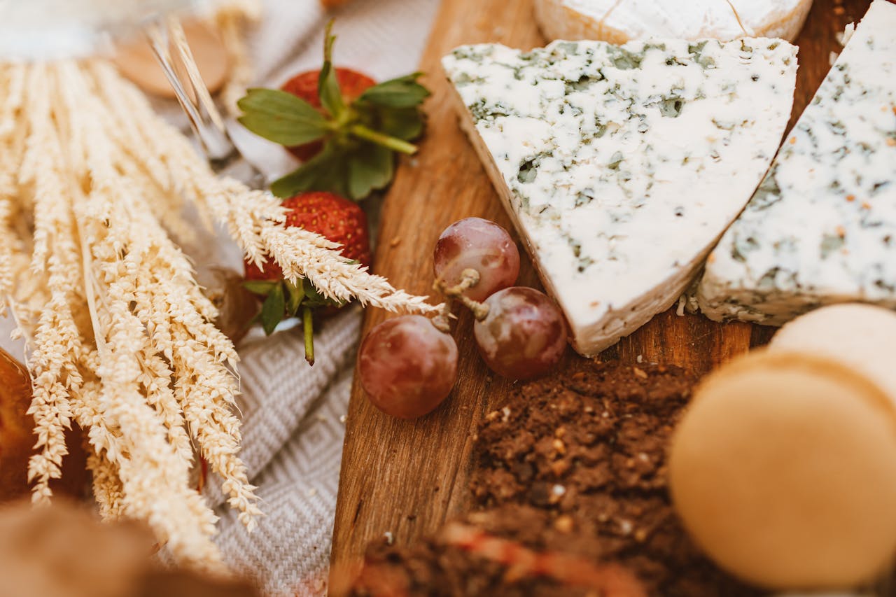 Home A rustic food platter featuring blue cheese, grapes, and strawberries on a wooden board.